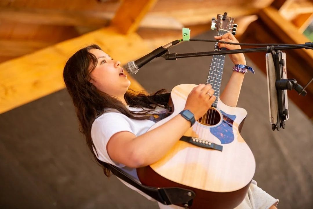 A musician passionately performing with a guitar on the AgeHa stage.