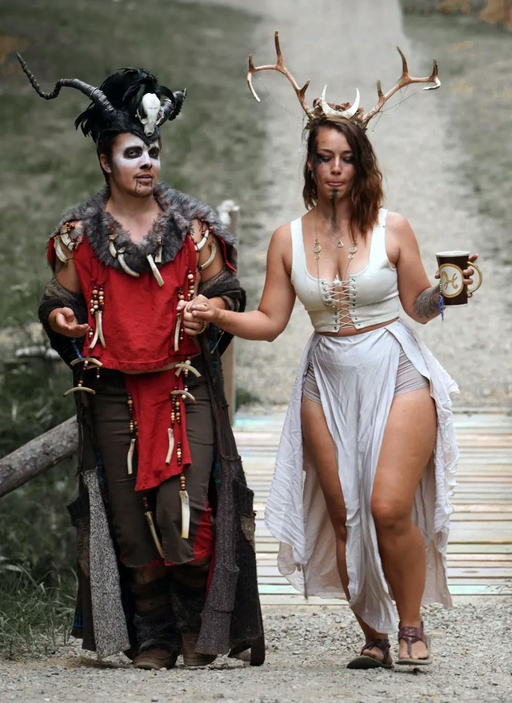 Two festival participants in elaborate costumes, one with a deer skull headdress.