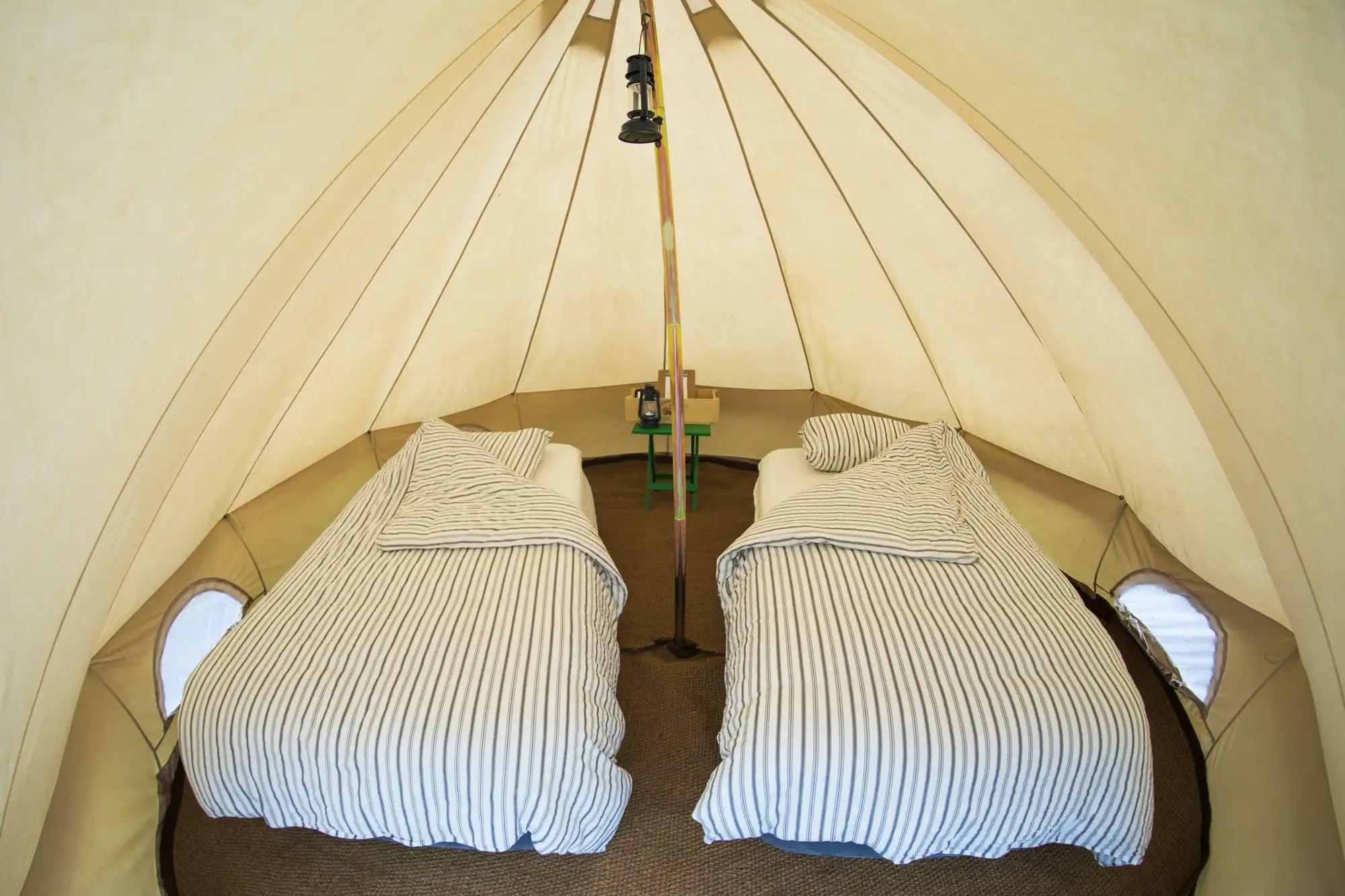 Interior of a tent with two beds and striped bedding.
