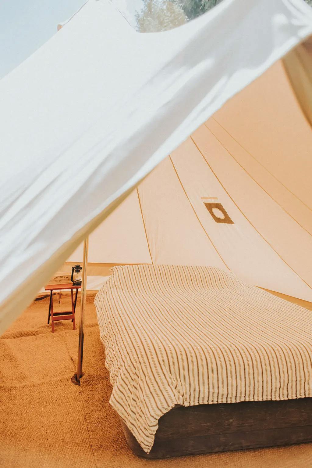 Cozy tent interior with a large bed and striped cover.
