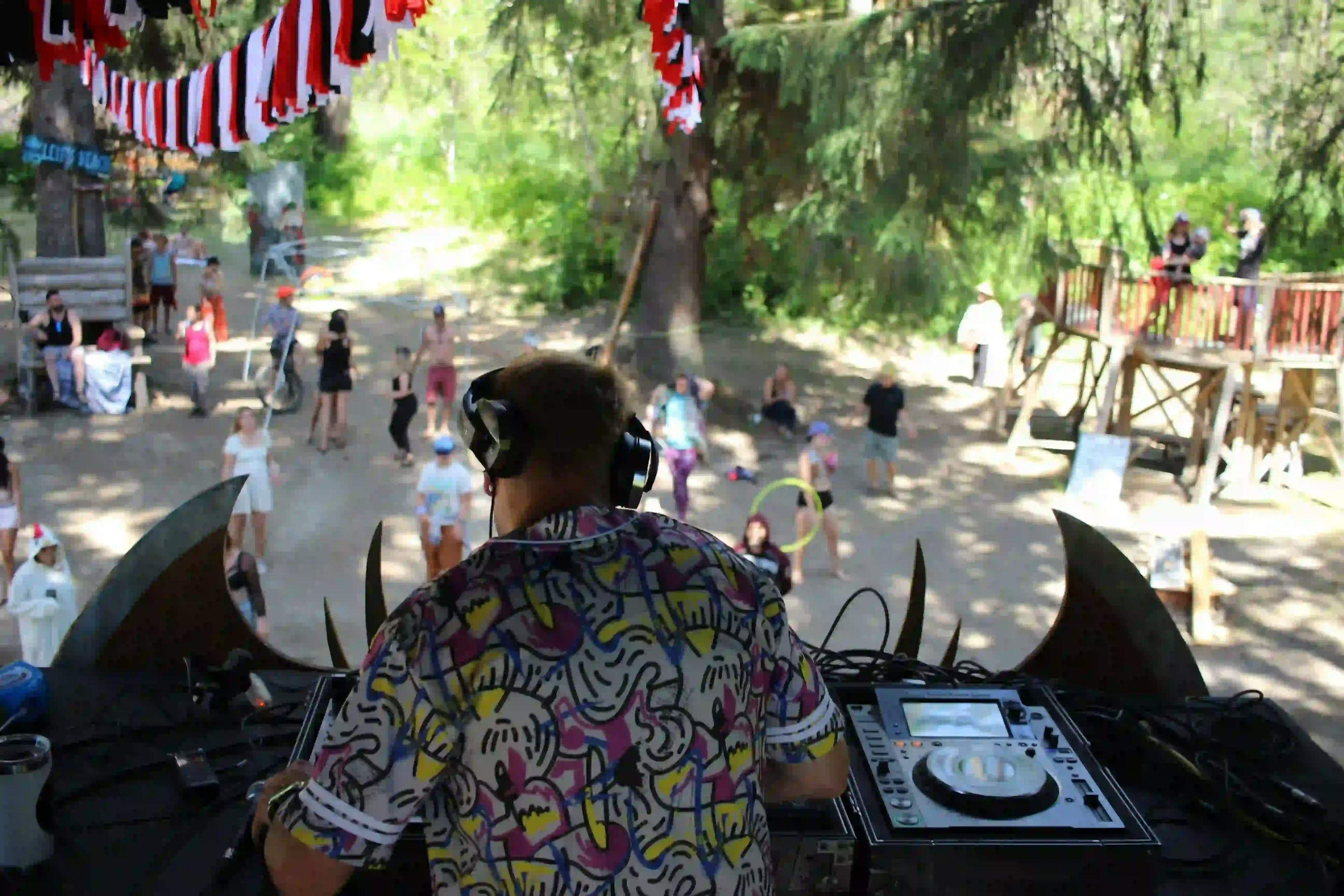 DJ performing at Leif's Beach stage with a crowd of festival attendees dancing in daylight.