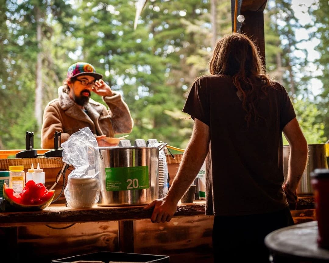 Person at a wooden bar inside a festival market area.