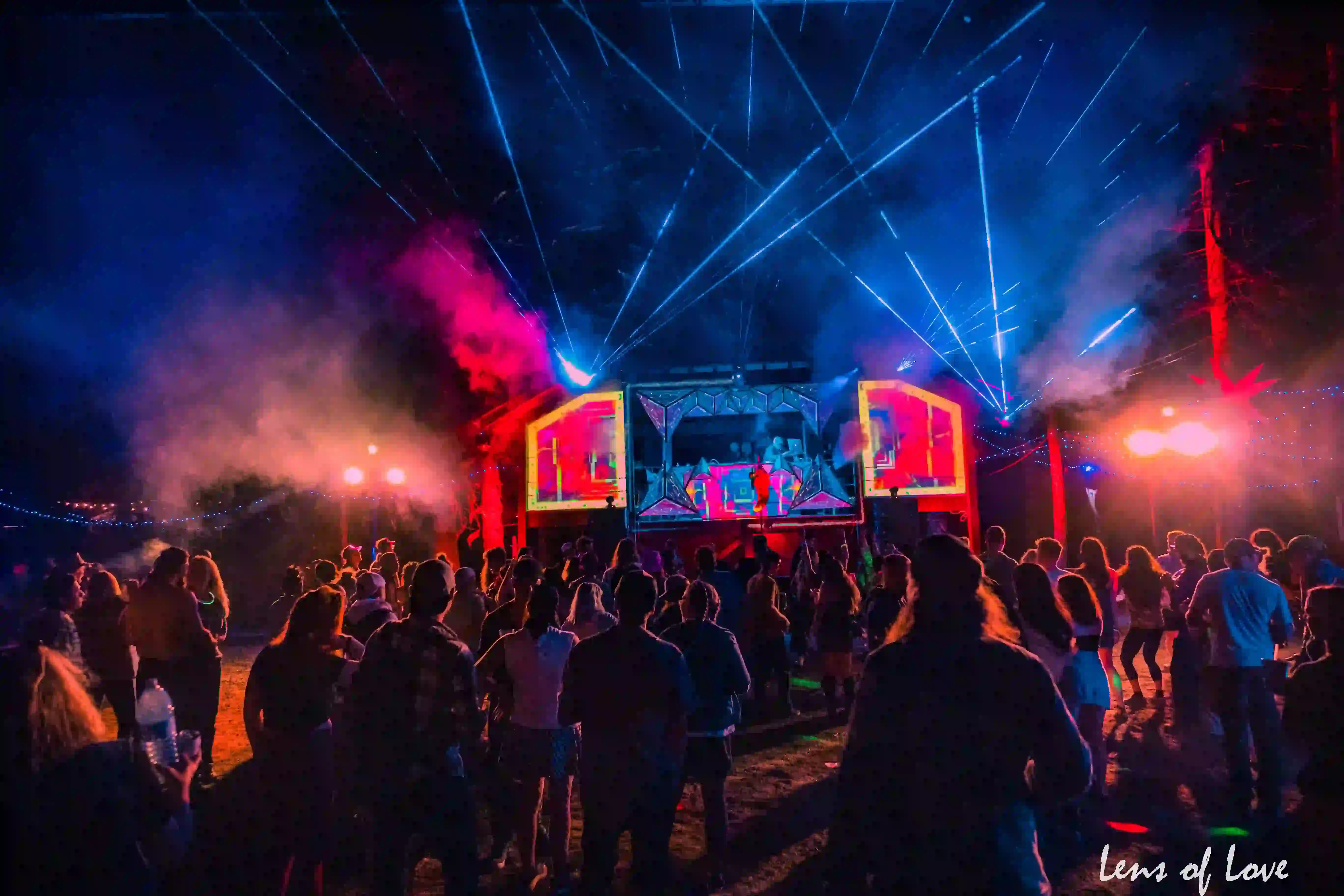 Asgard stage at night with dazzling light shows, lasers, and crowds enjoying the music.