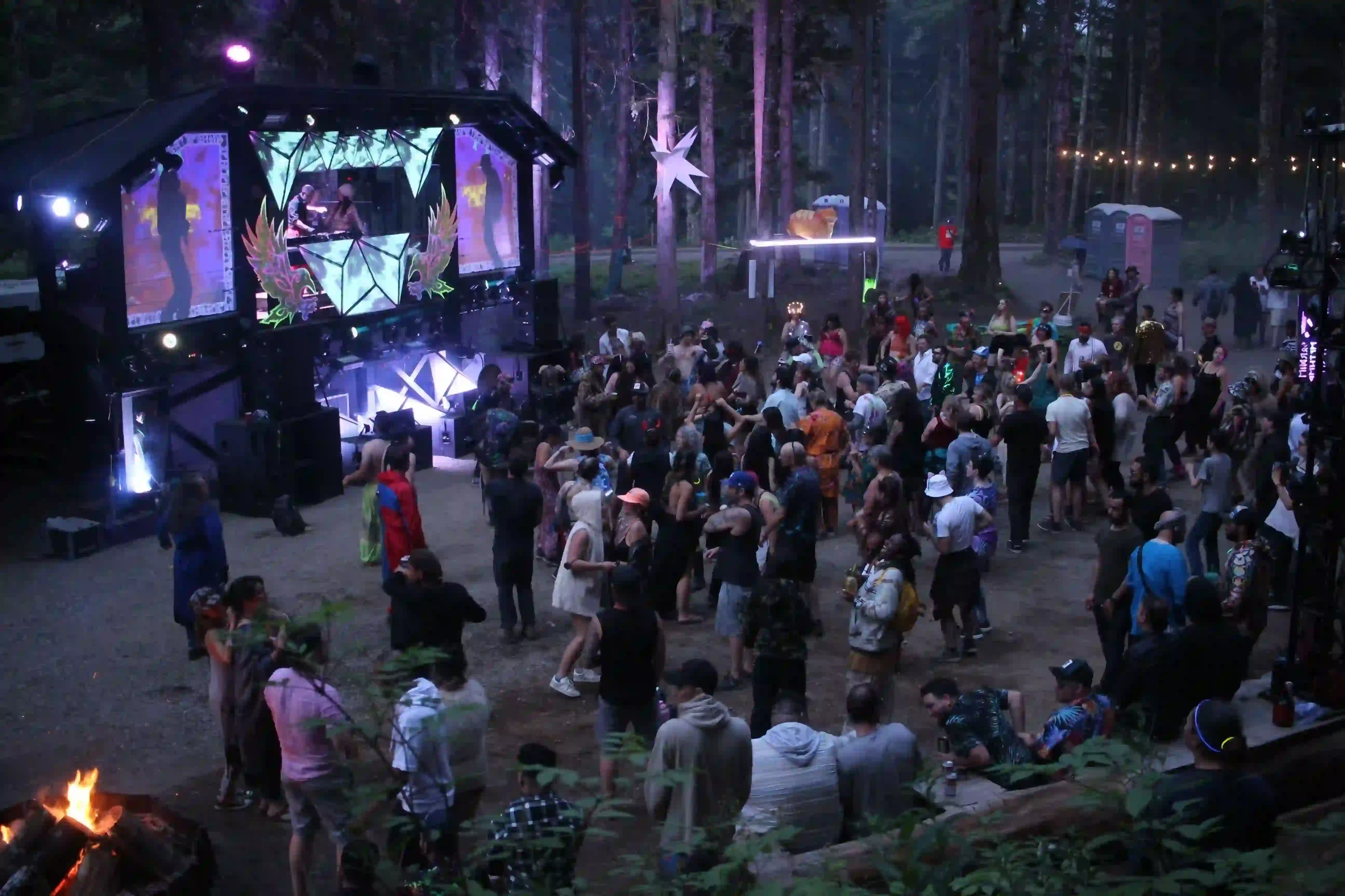 Asgard stage at night with dazzling light shows, lasers, and crowds enjoying the music.