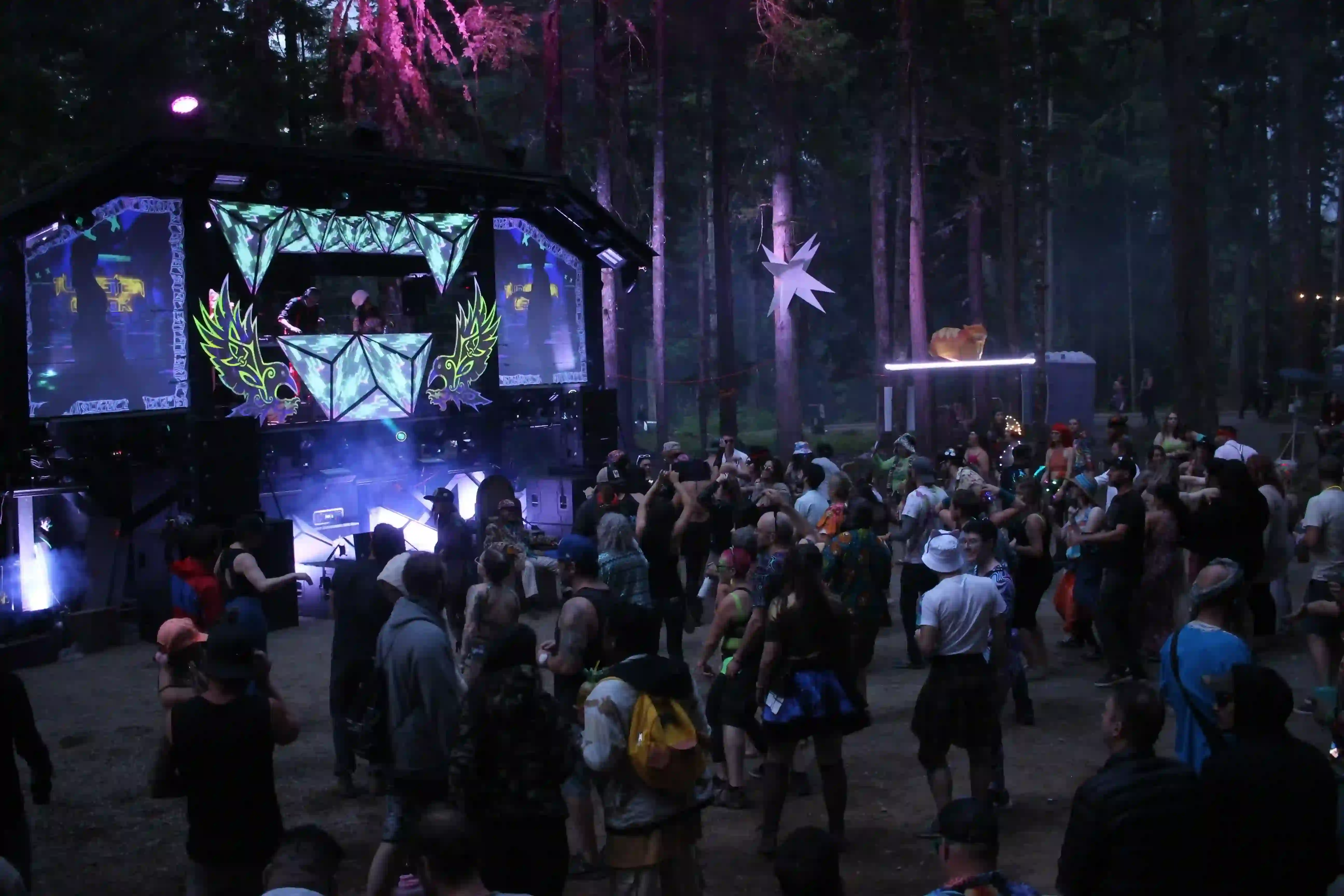 Asgard stage at night with dazzling light shows, lasers, and crowds enjoying the music.