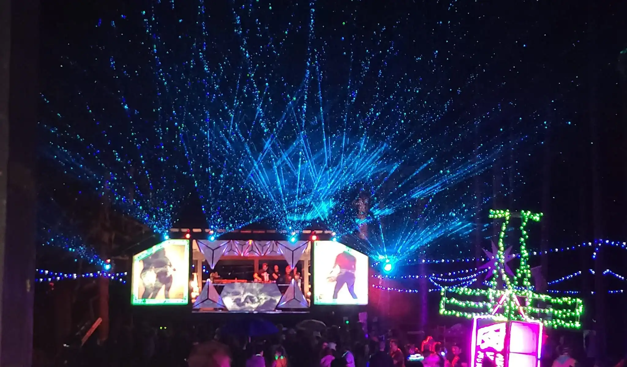 Asgard stage at night with dazzling light shows, lasers, and crowds enjoying the music.