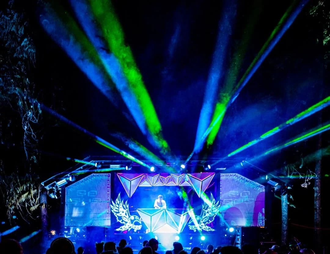 Asgard stage at night with dazzling light shows, lasers, and crowds enjoying the music.