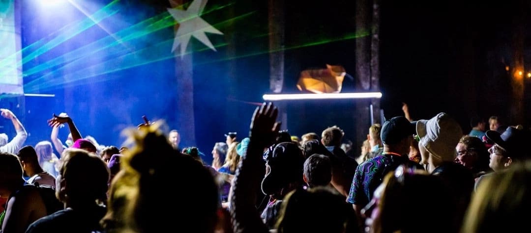 Asgard stage at night with dazzling light shows, lasers, and crowds enjoying the music.