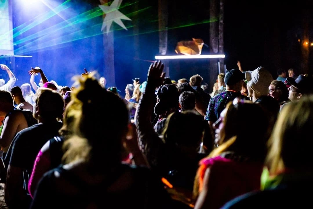 Asgard stage at night with dazzling light shows, lasers, and crowds enjoying the music.