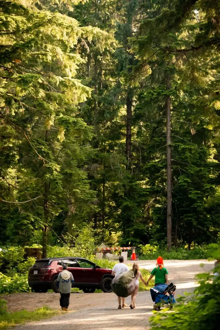 Camping at Valhalla with tents, campers, vehicles, and cabins in an old growth forest setting.