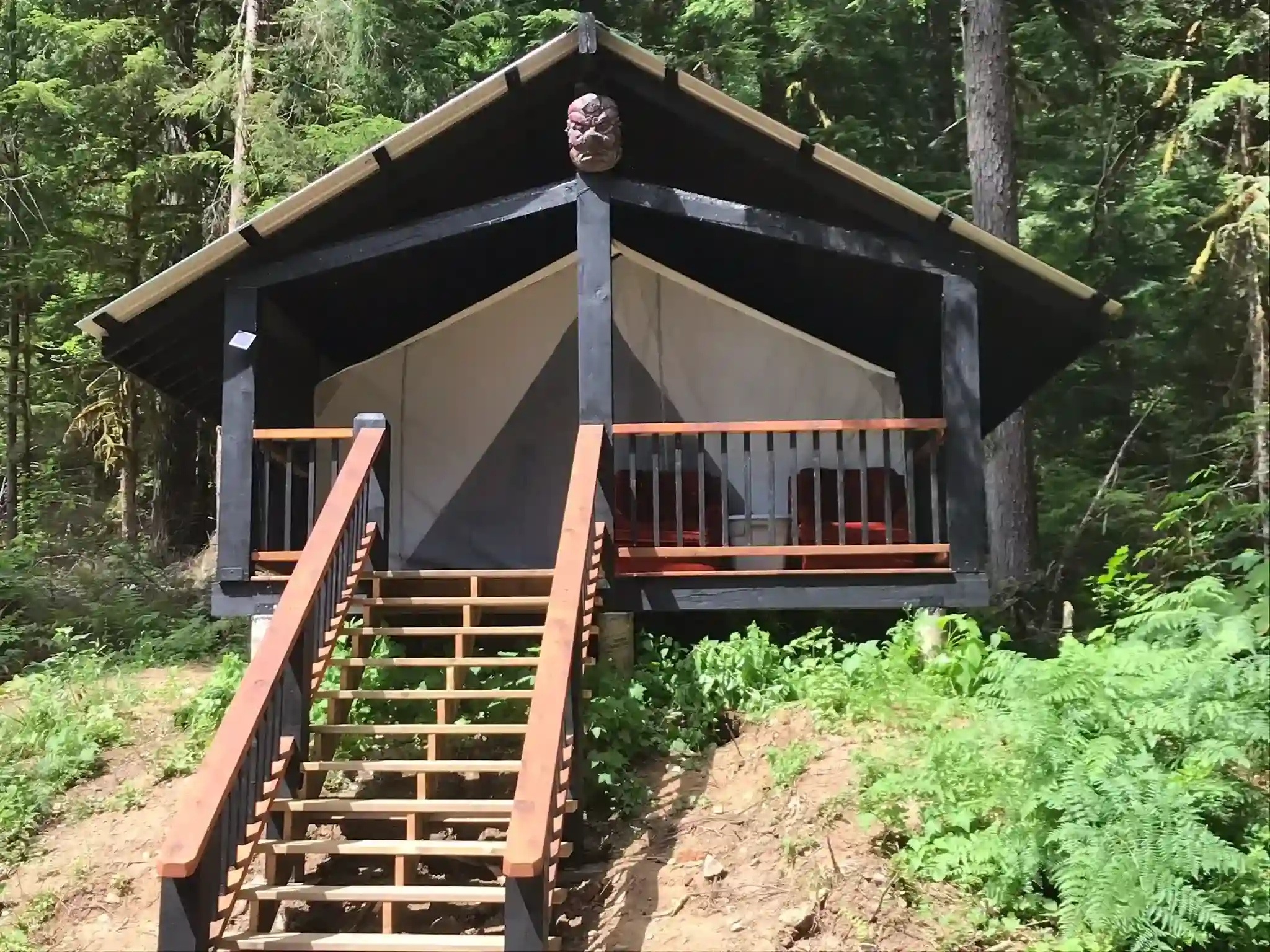 Camping at Valhalla with tents, campers, vehicles, and cabins in an old growth forest setting.