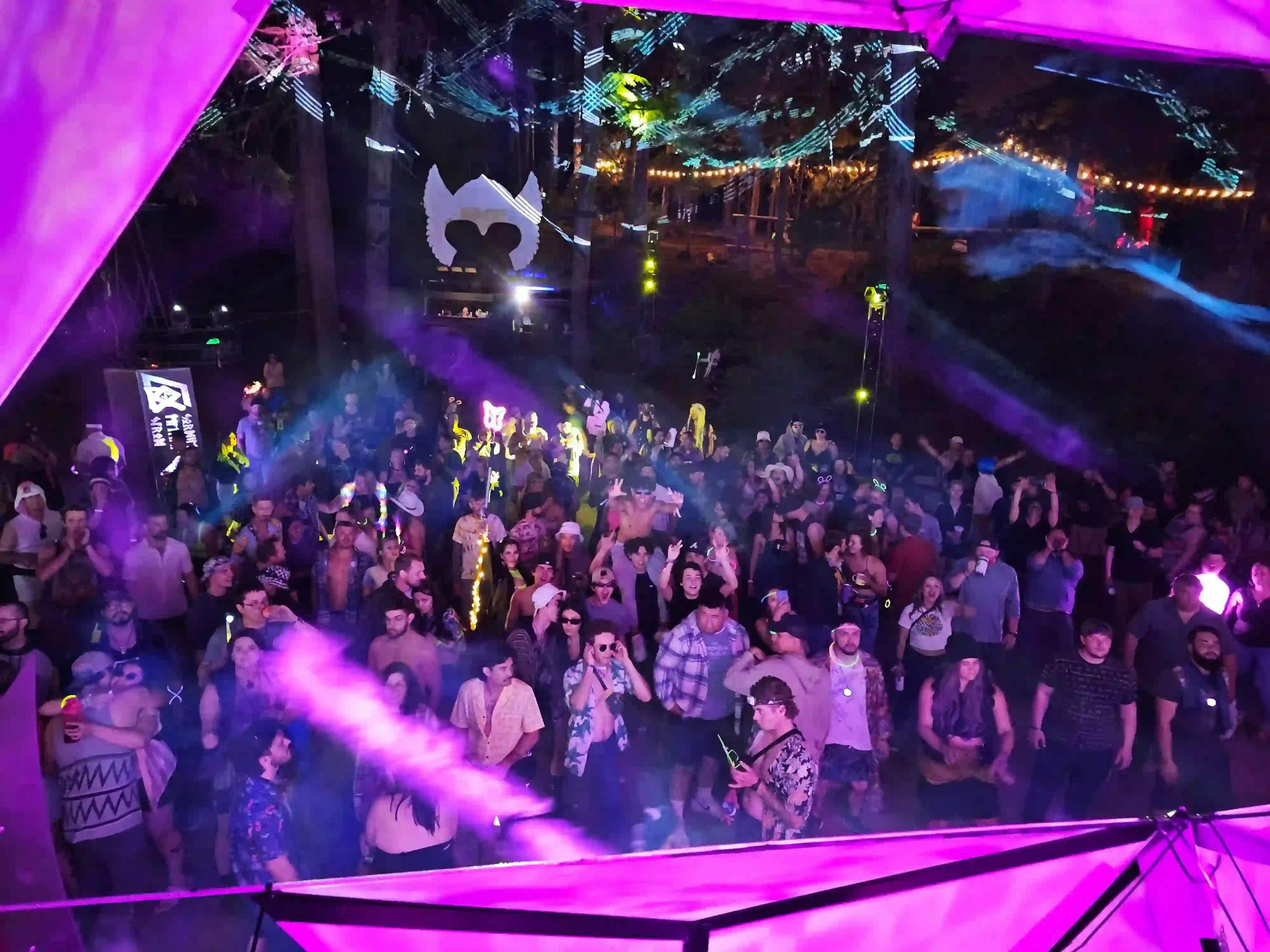 Aerial view of a lively crowd at the Asgard stage with colorful stage lights and festival ambiance.