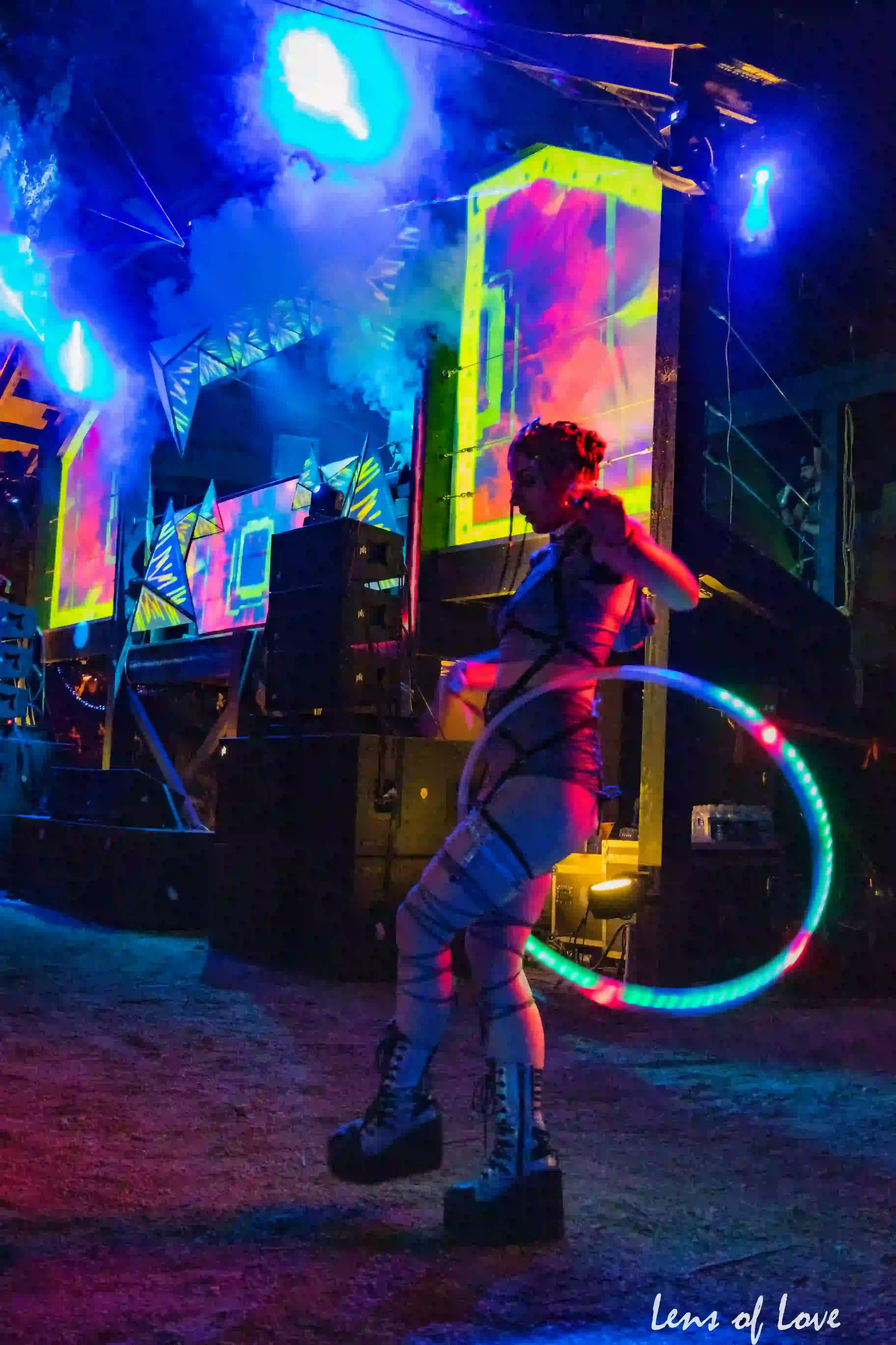 Performer hula hooping at ValhallaFest with colorful stage lights.