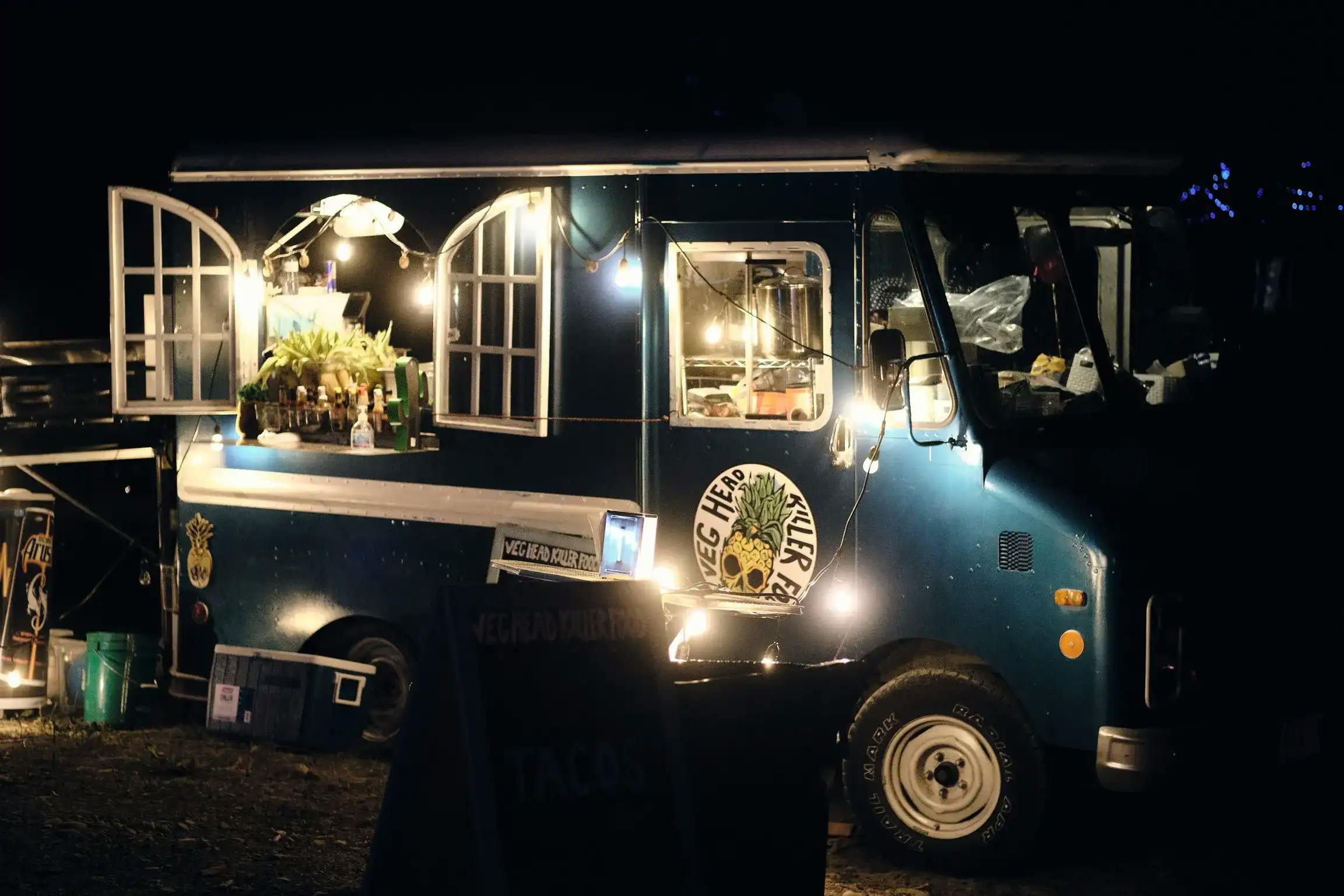 Illuminated food truck at night serving festival-goers.