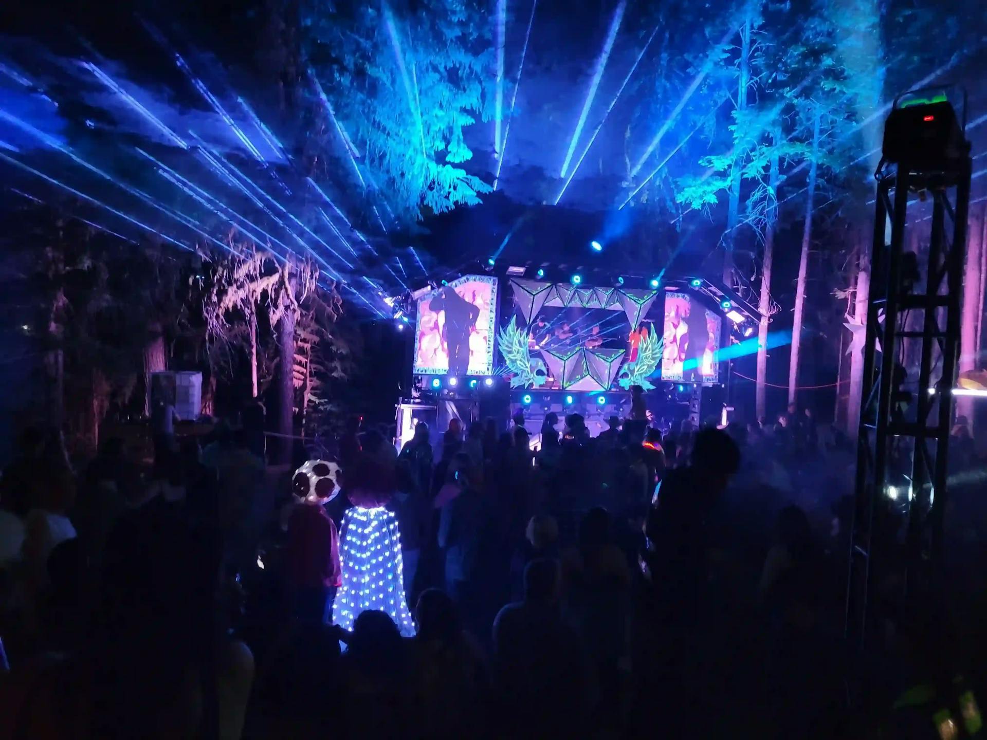 Asgard stage at night with dazzling light shows, lasers, and crowds enjoying the music.